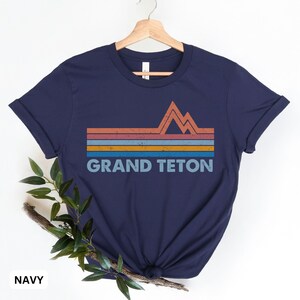 Puede incluir: Camiseta azul marino con un gr&aacute;fico de estilo vintage de una cordillera y el texto "GRAND TETON".