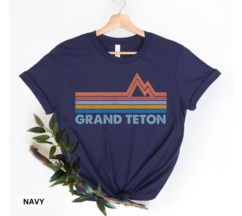 Puede incluir: Camiseta azul marino con un gr&aacute;fico de estilo vintage de una cordillera y el texto "GRAND TETON".
