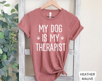 May include: A heather mauve t-shirt with the text "My dog is my therapist" and a paw print graphic.