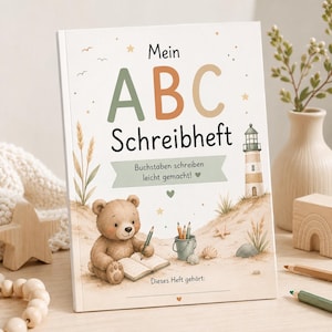 Pode incluir: Um caderno de exercícios intitulado Mein ABC Schreibheft com fundo claro, apresentando um urso de peluche castanho a escrever num caderno, um farol, conchas e estrelas. O texto diz Mein ABC Schreibheft, Buchstaben schreiben leicht gemacht! e Dieses Heft gehört:.