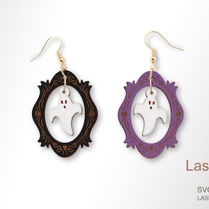 Op de afbeelding: Een paar lasergesneden houten oorbellen met een spook in een decoratief frame. De ene oorbel heeft een zwart frame en de andere een paars frame. LaserArtist studio SVG / PDF / DXF LASER-READY-BESTANDEN