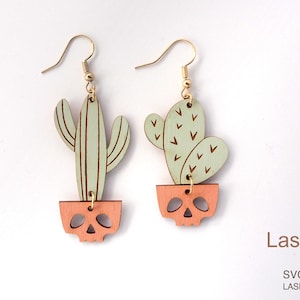 May include: A pair of wooden earrings featuring a cactus design. The cactus is green and has a pink skull-shaped pot. The earrings are laser cut and ready to be assembled. LaserArtist studio SVG / PDF / DXF LASER READY FILES