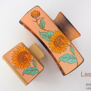 May include: Two hair clips featuring a sunflower and leaf design. The clips are made of brown and beige plastic. The sunflowers are yellow with orange centres and green leaves. The text "LaserArtist studio" is in the bottom right corner of the image.  SVG / PDF / DXF LASER READY FILES