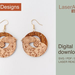 May include: Two wooden owl earrings with a moon and stars design. The earrings are laser cut and ready to be assembled.  "LaserArtist studio" and "Digital download" are printed on the image.