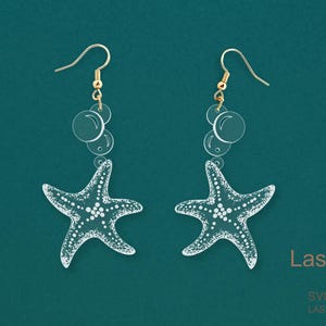 Puede incluir: Pendientes de estrella de mar de acrílico transparente con ganchos dorados y detalles de burbujas. Los pendientes están cortados con láser y presentan un diseño detallado. El fondo es de color verde azulado. El texto "LaserArtist studio" y "SVG / PDF / DXF LASER READY FILES" son visibles.