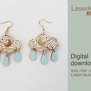 Puede incluir: Un par de pendientes de madera cortados con láser que presentan una nube con una luna creciente y estrellas, y tres gotas de lluvia colgando debajo. Los pendientes son de color madera claro con detalles dorados. El texto "LaserArtist studio" y "Descarga digital SVG / PDF / DXF ARCHIVOS LISTOS PARA LÁSER" es visible en el fondo.