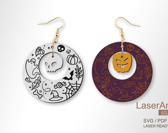 May include: A pair of Halloween-themed earrings. One earring is white with black details and features a skull, ghost, and other spooky elements. The other earring is purple with gold details and features a jack-o'-lantern, ghost, and other spooky elements. Both earrings are round and have a gold hook.