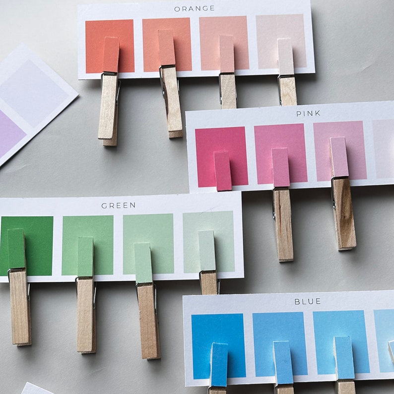 May include: A set of color swatches with wooden clothespins. The swatches are labeled "Orange", "Pink", "Green", and "Blue".