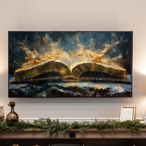 Puede incluir: Un mueble de entretenimiento para sala de estar con una gran obra de arte enmarcada que representa un libro abierto con páginas doradas. Dos lámparas grises con pantallas beige flanquean la obra de arte. El mueble de madera está decorado con vegetación y objetos decorativos.