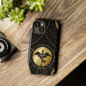 Könnte beinhalten: Schwarze Handyhülle mit goldenem Sternenbild-Design und einem goldenen Kreis mit dem Text "You are my gravity, nothing in my world works without you". Der Kreis zeigt auch eine Silhouette eines Drachen.