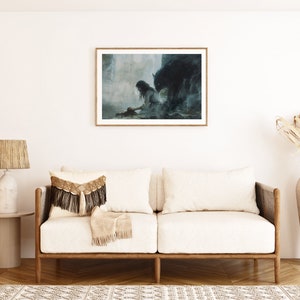 May include: A framed painting depicting a woman in a white dress kneeling before a shadowy figure. The artwork is displayed on a white wall in a living room featuring a sofa, a lamp, and a vase of dried flowers.