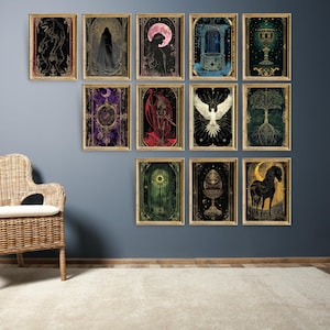 May include: A collection of framed art prints with mystical and gothic themes. Each print features detailed illustrations in dark colors, including figures, celestial bodies, and symbolic imagery. The prints are displayed on a blue wall.