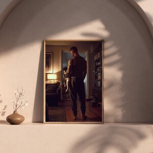 May include: A framed photograph of a person holding a small animal, likely a pet. The photograph is displayed on a shelf with a vase and decorative plant. The room is dimly lit with warm tones.