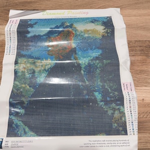 May include: A diamond painting kit featuring a colorful image of a person in a landscape. The kit includes a canvas, rhinestones, and instructions. The text "Diamond Painting" is visible at the top.