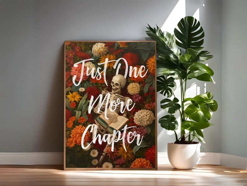 May include: A framed print with a skeleton laying on a book surrounded by colorful flowers. The text "Just One More Chapter" is written in white on the print.