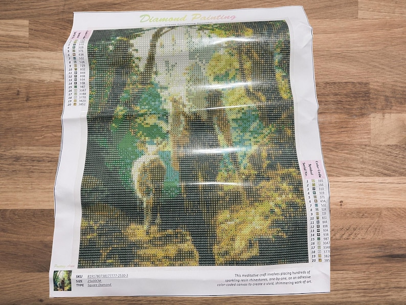May include: A diamond painting kit featuring a forest scene with a deer. The image is composed of small, colorful squares, creating a mosaic effect. The kit includes a canvas, color codes, and instructions.