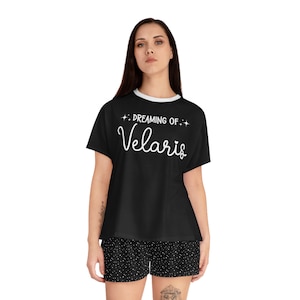 May include: Black pajama set with white trim, featuring a top with the text "Dreaming of Velaris" in white script. The shorts are black with a white polka dot pattern. A comfortable sleepwear set.
