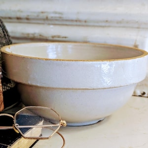 Puede incluir: Un juego de tres tazas de cerámica con acabado mate moteado. Las tazas son de color crema, marrón claro y marrón oscuro. Cada taza tiene un diseño simple y minimalista.