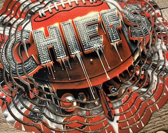 May include: A red, white and black metal wind spinner with the word "CHIEFS" in large, glittery letters. The letters are dripping with a white substance, and the background is a football with white stitching.