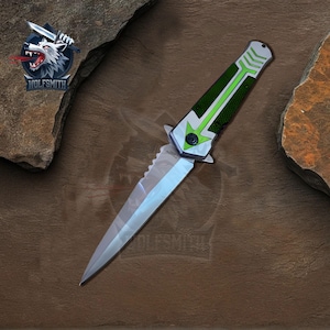 May include: A silver folding knife with a green and black handle. The handle has a green arrow design.