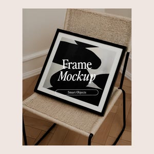 Puede incluir: Un marco negro con una impresión de arte abstracto en blanco y negro, apoyado en una silla de mimbre. El marco tiene el texto "Frame Mockup" y "Smart Objects" en blanco.