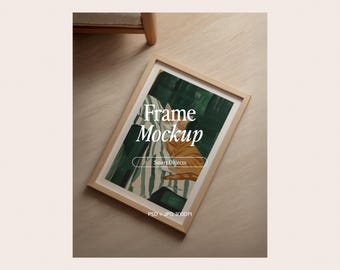 May include: A wooden framed mockup with an abstract painting featuring green and white stripes and an orange cat. The text "Frame Mockup" is displayed in white, along with "Smart Objects". The image is on a light brown surface.