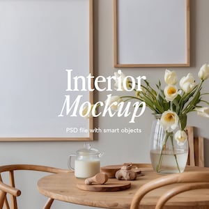 Puede incluir: Una mesa de madera con dos sillas, un jarrón de tulipanes blancos, una jarra de leche y dos cuadros enmarcados en la pared. La mesa está puesta con una tabla de cortar de madera y algunos objetos de madera.