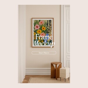 May include: A framed floral art print with a wooden frame hangs on a beige wall. The artwork features colorful flowers in pink, yellow, and blue. The text "Frame Mockup" is overlaid on the image, along with "Smart Objects". A small wooden stool and a side table are below.