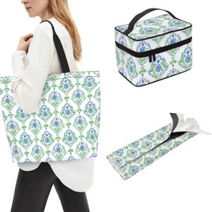 May include: A large tote bag, a rectangular cosmetic case with a black handle and zipper, and a slim folding pouch, all featuring a white background with a repeating blue rose and green leaf damask-style pattern and black trim accents.