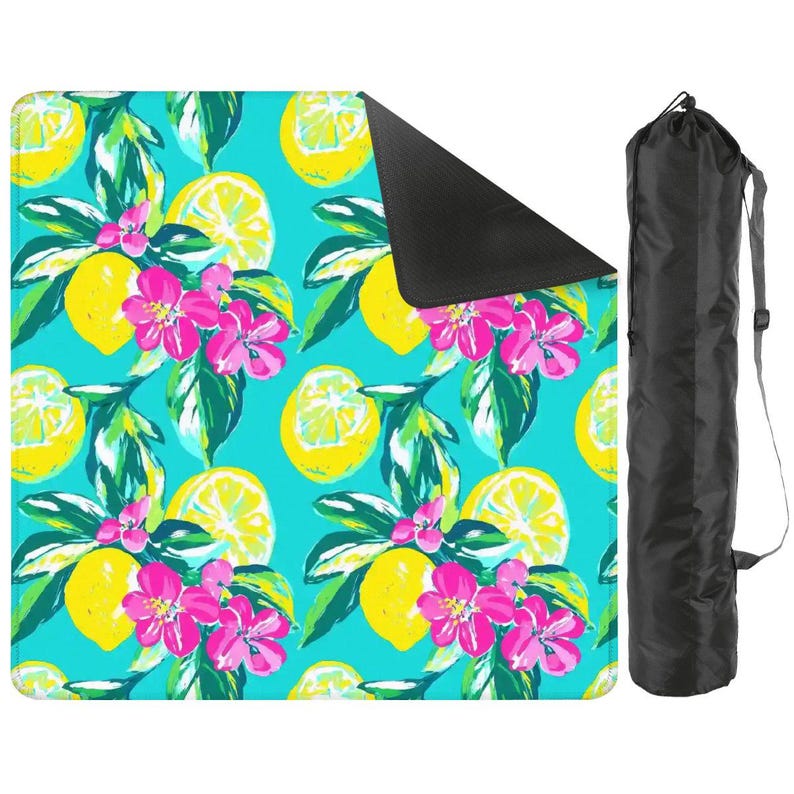 May include: A turquoise picnic blanket with a vibrant lemon and floral pattern. The design features yellow lemons, pink flowers, and green leaves. A black carrying bag with a shoulder strap is included.