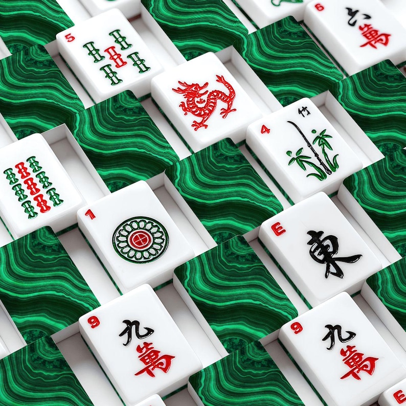 May include: A collection of white Mahjong tiles with red and green symbols and numbers, arranged in individual boxes with a green, marbled pattern. The tiles feature various designs, including dragons, bamboo, and floral patterns.