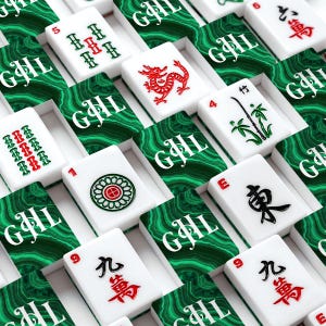 May include: A close-up shot of a Mahjong set with white tiles featuring red and green symbols and characters. The tiles are arranged in rows, with each tile resting on a green and white patterned surface. The set includes tiles with numbers, bamboo, and Chinese characters.
