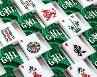 May include: A close-up shot of a Mahjong set with white tiles featuring red and green symbols and characters. The tiles are arranged in rows, with each tile resting on a green and white patterned surface. The set includes tiles with numbers, bamboo, and Chinese characters.