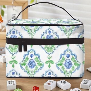 May include: A white cosmetic bag with a blue and green floral pattern, a black zipper, and a black handle. Mahjong tiles and dice are scattered on a wooden surface.