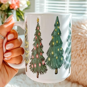 May include: A white ceramic mug featuring a repeating illustration of stylized Christmas trees. The trees are depicted in various shades of green with colorful ornaments and yellow star toppers. The mug has a smooth, glossy finish and a curved handle.