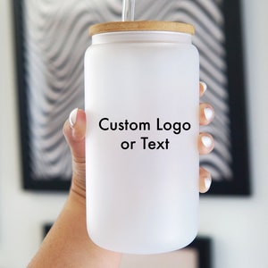 May include: White frosted glass tumbler with a wooden lid and a straw. The tumbler has the text "Custom Logo or Text" printed on the front.