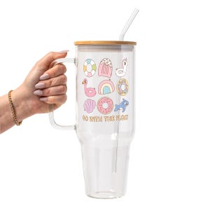 May include: A clear glass tumbler with a bamboo lid and a glass straw. The tumbler features colorful illustrations of pool floats and the text "GO WITH THE FLOAT". The handle is clear.