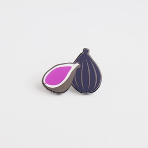 Puede incluir: Un pin de esmalte morado y azul oscuro con forma de higo.