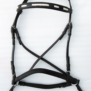 Puede incluir: Bridón de cuero negro para caballo con frontal trenzado blanco.