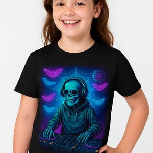 May include: Black t-shirt featuring a neon illustration of a DJ skeleton wearing headphones and a hoodie. The design includes bats, a disco ball, and a spiderweb background. The skeleton is operating a DJ mixer.