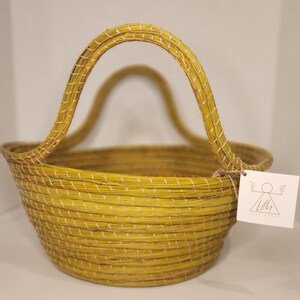 May include: A yellow woven basket with a single handle. The basket is made of natural materials and has a rustic look.