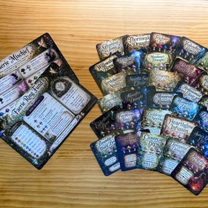 May include: A tabletop game set featuring two large instructional cards titled Faerie Mischief and Faerie Ring Fund, alongside a collection of smaller rectangular cards with dark, magical illustrations of mushrooms and various potion names.
