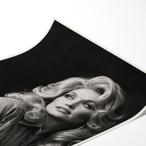 May include: A black and white photographic print featuring a portrait of a person with voluminous, wavy blonde hair styled in a classic bouffant. The subject is wearing a collared shirt and is positioned against a dark, solid black background.