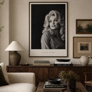 May include: A large black and white portrait print of Dolly Parton in a dark frame hanging on a wall. The photograph features the subject with voluminous hair, wearing a collared shirt, with the text Dolly Parton Tennessee printed at the bottom.