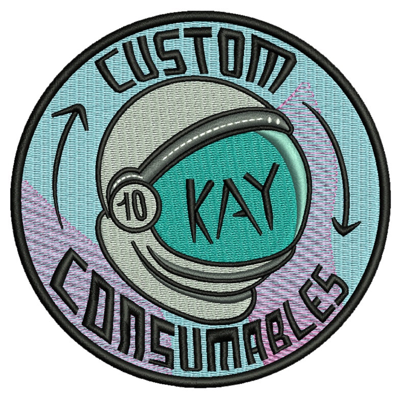 May include: A round, blue and pink embroidered patch with a white astronaut helmet and the text "CUSTOM 10 KAY CONSUMABLES" in black.