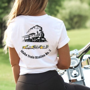 May include: White t-shirt with a black and white illustration of a train engine with smoke coming from the chimney. The text "Idaho Train Station No. 5" is printed below the train.
