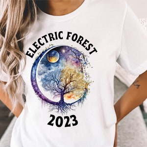 May include: White t-shirt with a black and white graphic of a tree with roots, a moon, and stars in a circle. The text "ELECTRIC FOREST 2023" is printed on the shirt.