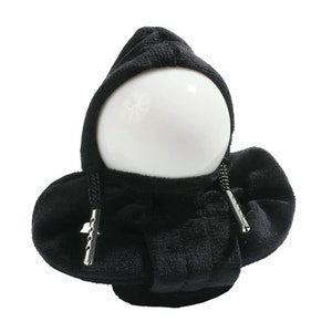 Op de afbeelding: Zwart pluche speelgoed met capuchon, een witte bolvormige kop en zwarte trekkoordjes.