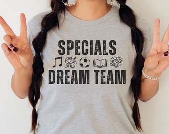 May include: A gray t-shirt with the text "Specials Dream Team" in black. The text is in a distressed font and is surrounded by icons representing music, art, sports, reading, and a lightbulb.