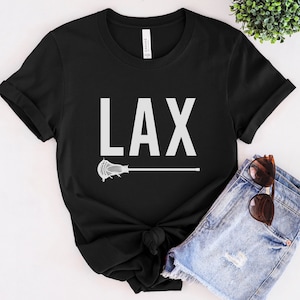 May include: Black t-shirt with white text that says "LAX" and a white lacrosse stick graphic.